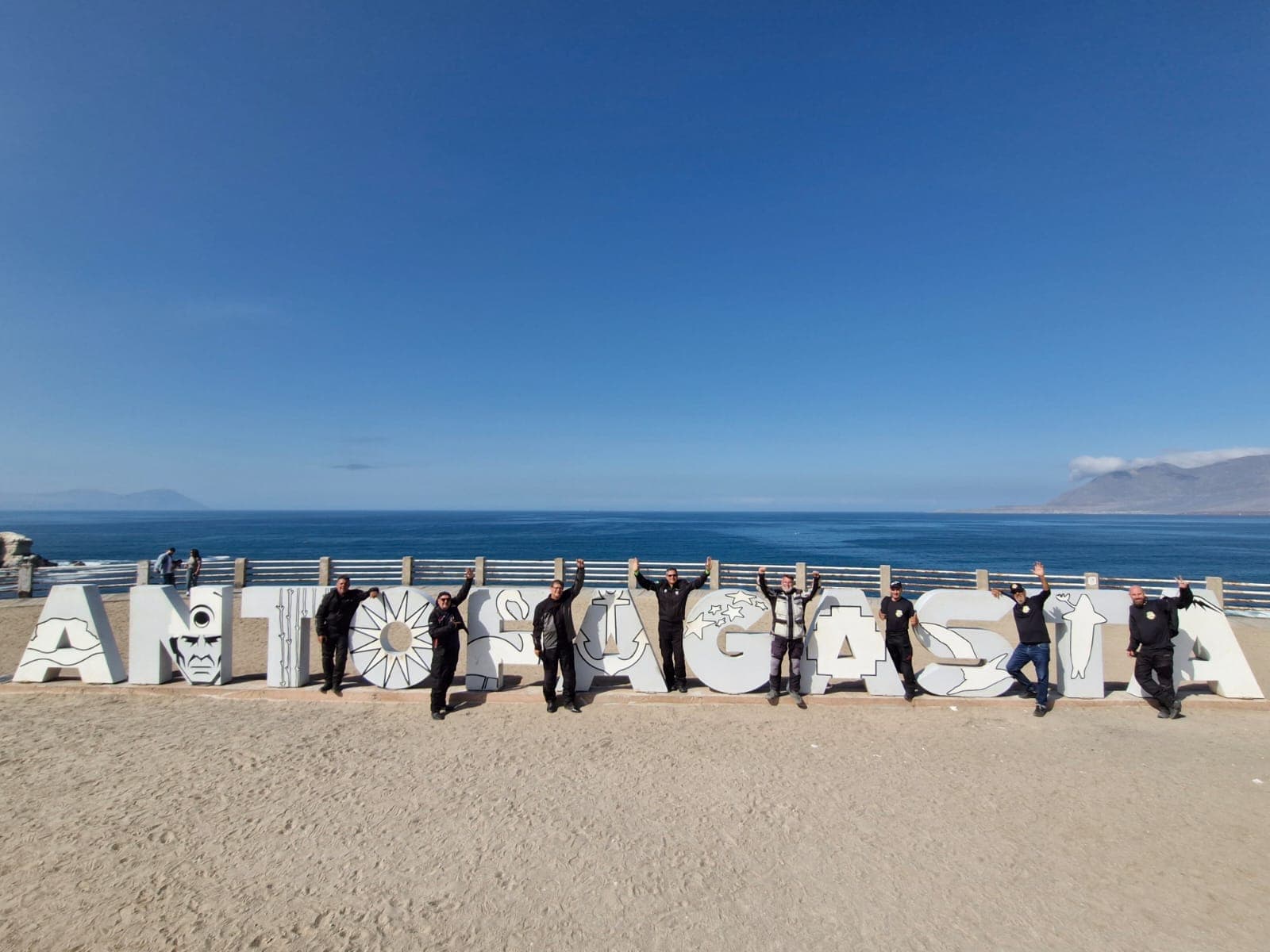 Grupo posando entre as letras gigantes de ANTOFAGASTA, com o Pacífico ao fundo